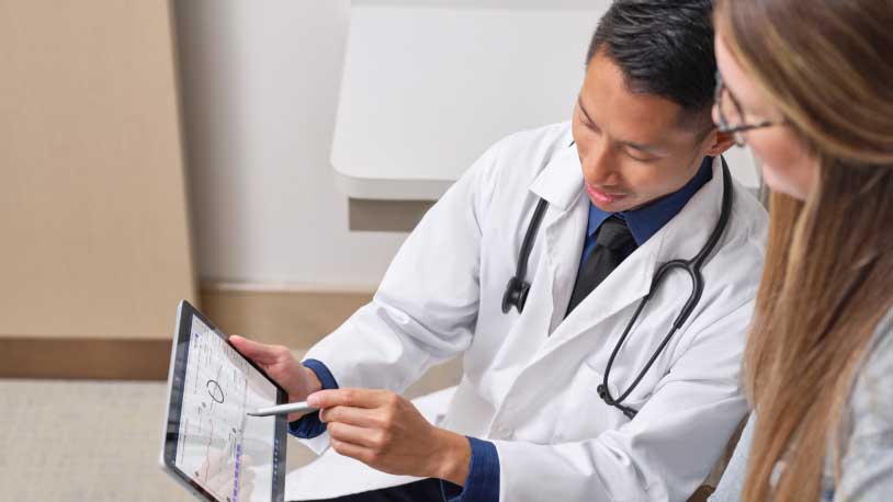一位醫生大概是在平板電腦裝置上向患者展示一些資料